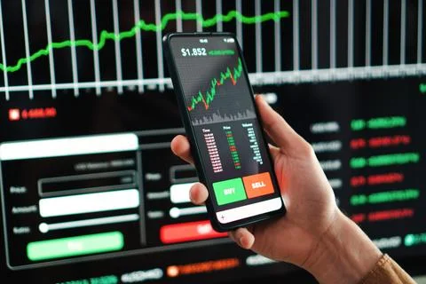 Crypto trader broker using a cell phone financial app to buy or sell shares of Stock Photos