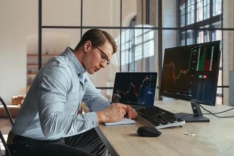 Crypto trader noting down info in notepad after checking ico and trading market Stock Photos