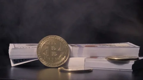 Cryptocoins and  two stacks of hundred dollar bills rotating slowly Stock Footage 217947086