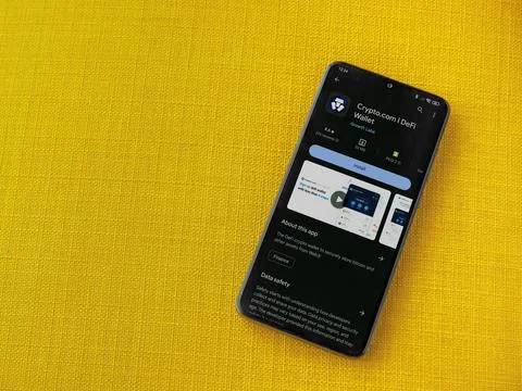 Crypto.com app play store page on smartphone on a yellow fabric background Stock Photos