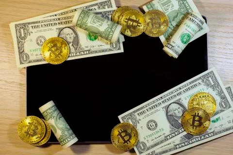 The cryptocurrency Bitcoin and dollars on the background of tablet computer Stock Photos