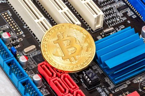 Cryptocurrency Bitcoin lying over electronic computer component Stock Photos
