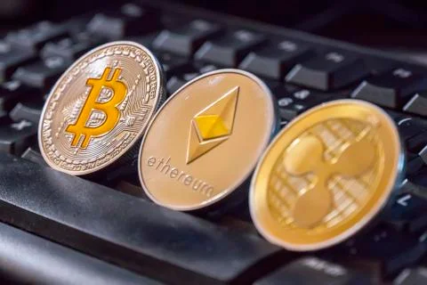 Cryptocurrency coins over black keyboard; Bitcoin, Ethereum and Ripple coins Stock Photos