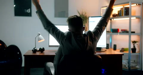 Cryptocurrency day trader celebrating big profits at his computer desk, behi Stock Footage 160987537