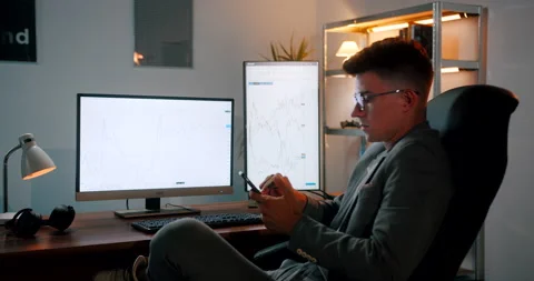 Cryptocurrency day trader checking graphs and making adjustments on his smar Stock Footage 160977745