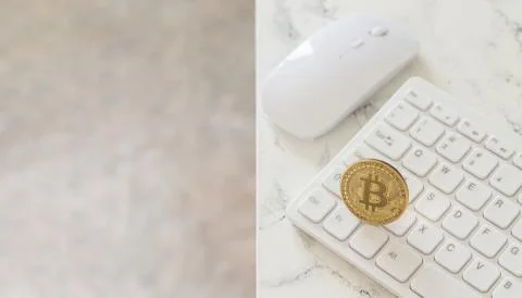 Cryptocurrency gold bitcoin on white computer keyboard on marble table Stock Photos