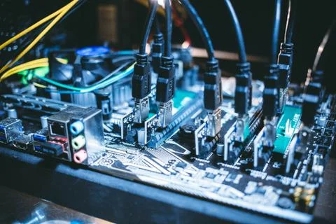 Cryptocurrency mining rig PCIe riser extenders plugged to motherboard. Stock Photos