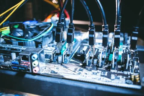 Cryptocurrency mining rig PCIe riser extenders plugged to motherboard. Stock Photos