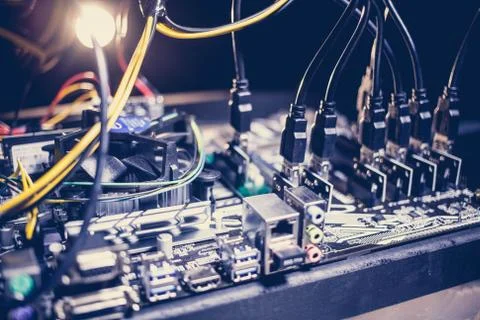 Cryptocurrency mining rig PCIe riser extenders plugged to motherboard. Stock Photos