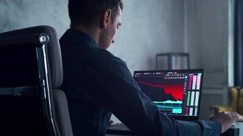 Cryptocurrency Trader at his Workplace in front of a Computer. Man Commits Stock-Footage 195815291