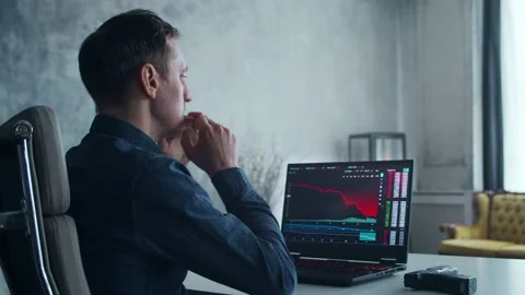 Cryptocurrency Trader at his Workplace in front of a Computer. Man Commits Stock Footage 195815558