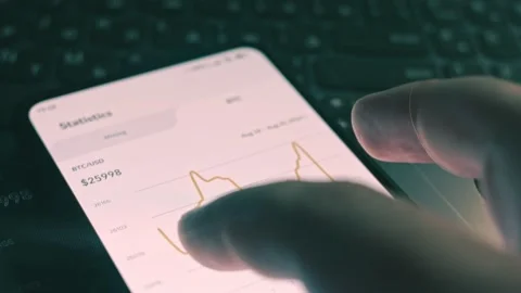 Cryptocurrency trading chart. Investor checking Bitcoin price index on mobile Stock Footage 249887606
