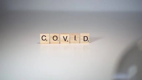 Crystal ball knocks down a wooden barrier on which is written the word "Covid Stock Footage