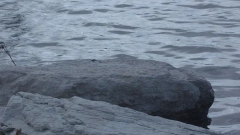 Crystal blue lake with rolling waves and large rocks in foreground. Slow motion. Stock Footage 88684228