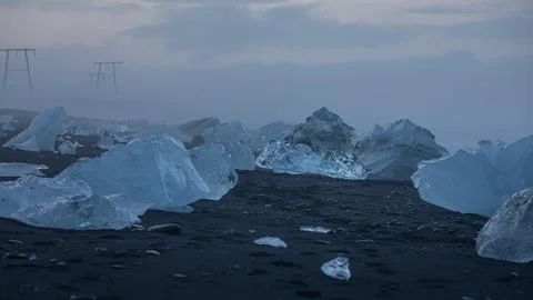 Crystal clear, blue chunks of ice on the black sand of Diamond Beach. Stock Photos
