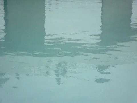 Crystal clear blue water in a pool with outside reflections and gentle waves Stock Footage 134334914