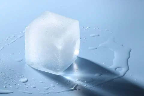 Crystal clear ice cube on light blue background, space for text 스톡 사진