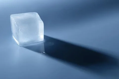 Crystal clear ice cube on light blue background, space for text Foto stock