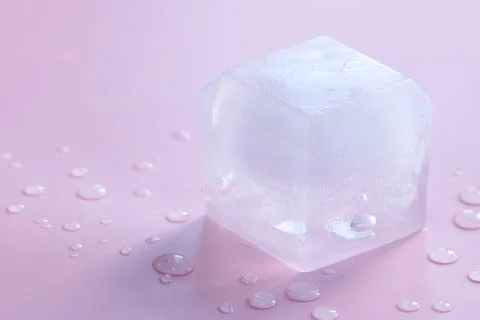 Crystal clear ice cube on light pink background, closeup. Space for text Stock Photos