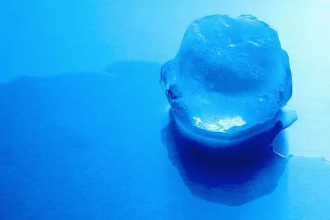 Crystal clear ice cube on light blue background, space for text. Color tone.. 스톡 사진