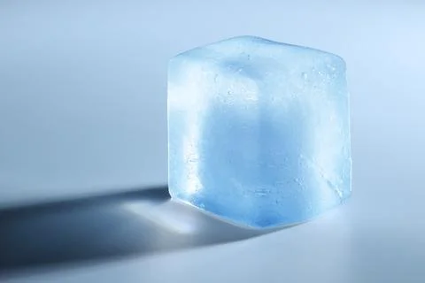 Crystal clear ice cube on light blue background, closeup. Space for text Stockfoto's