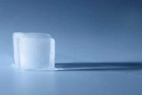 Crystal clear ice cube on light blue background, space for text Foto stock