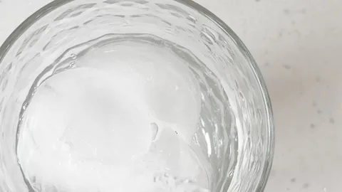 Crystal-clear ice cubes immersed in sparkling water create a refreshing frozen t Stock Footage 332850805