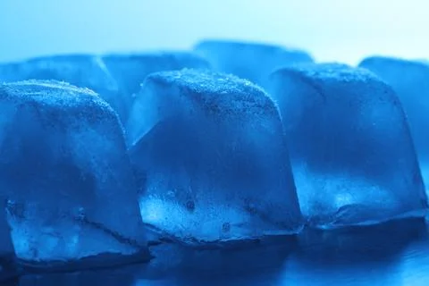 Crystal clear ice cubes on light blue background, closeup. Color tone effect 스톡 사진