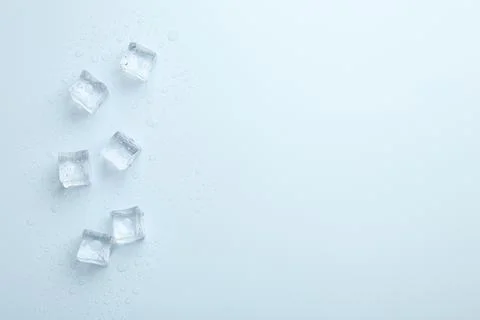 Crystal clear ice cubes on light blue background, flat lay. Space for text Foto stock