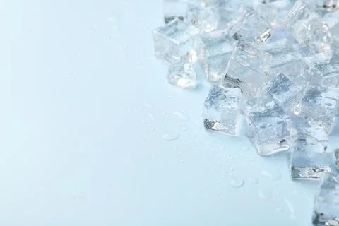 Crystal clear ice cubes on light blue background, closeup. Space for text Foto stock