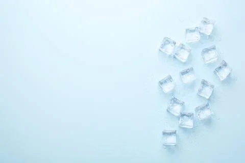 Crystal clear ice cubes on light blue background, flat lay. Space for text Foto stock