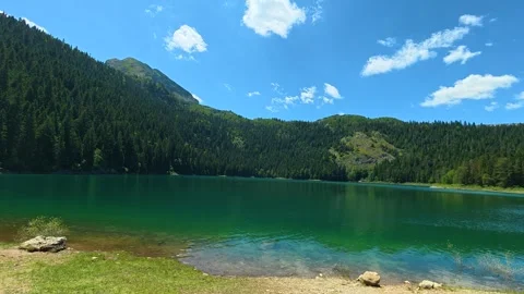 Crystal-clear lake reflects blue sky and fluffy clouds. Black Lake, Montenegro Видео 342972136