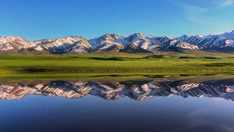 Crystal Clear Mirror Reflection of Snowy Peaks on Alpine Lake under Blue Sky Stock Footage 333726250