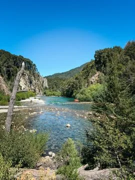 Crystal clear river flowing between forested cliffs Stock Photos