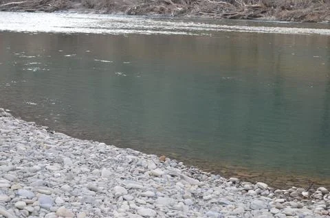 Crystal clear river flows gently beside smooth stone banks in a serene natural Stock Photos