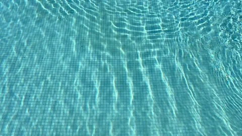 Crystal clear turquoise swimming pool water with sunlit ripples.  Vidéo 326465014