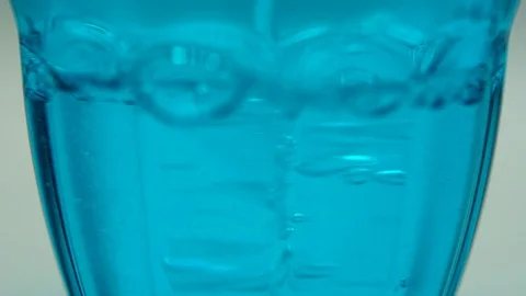 Crystal clear water drops falling inside the blue glass. Bubbles in the water Stock-Footage 108803780