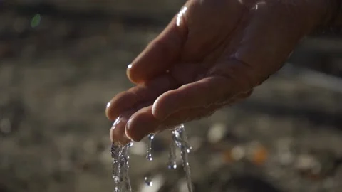 Crystal clear water falling into one hand. Focus on hand. Slow motion. Stock Footage 154407064