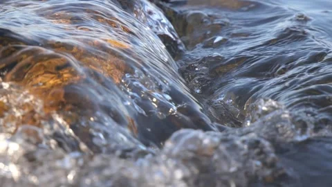 Crystal clear water flowing rapidly over smooth wet coastal rocks Stock Footage 337409124