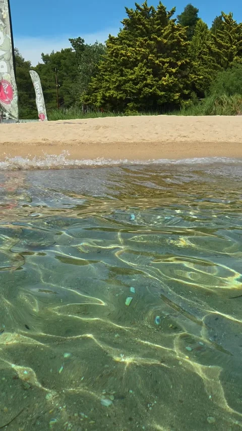 Crystal clear water laps soft golden sand. Kalogria, Greece. Vertical Stock Footage 338358357