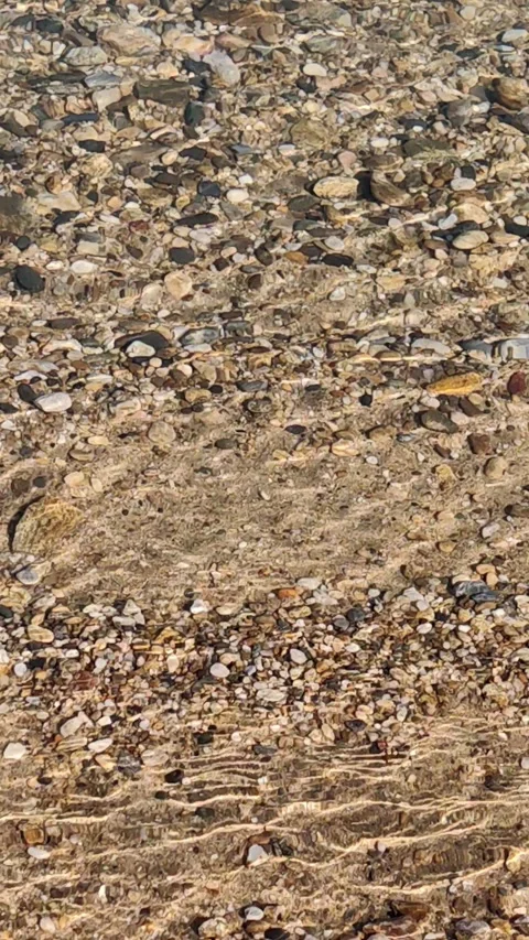 Crystal clear water rippling over pebbles and sand. vertical. Видео 331509012