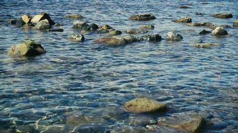 Crystal clear water on a stony shore slow motion Stock Footage
