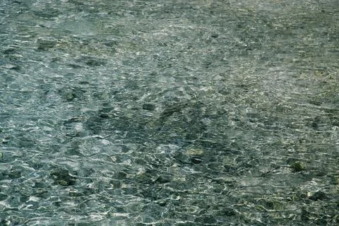 Crystal clear water texture background with ripples and visible pebbles on .. Stock Photos