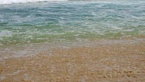 Crystal clear waves roll onto sandy beach, gentle sea foam retreats back to Stock Footage 270571311