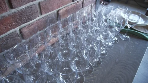 Crystal clear wine glasses on a table against a brick wall Stock Footage 108998612