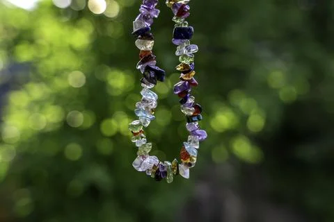 Crystal gemstone bracelet talisman charged in the sunlight, nature green bokeh Stock Photos