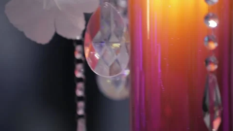 A crystal with many facets hangs against a backdrop of flower decorations Stock Footage 130215982