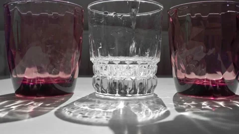 Crystal red glass on white table. Hard shadows in sunlight. Vidéo 137703266