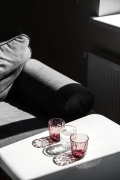 Crystal red glass on white table. Hard shadows in sunlight. Stock Photos