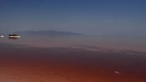Crystal salt rock inside the red pink sea water with mountains in the background Stock Footage 70355794